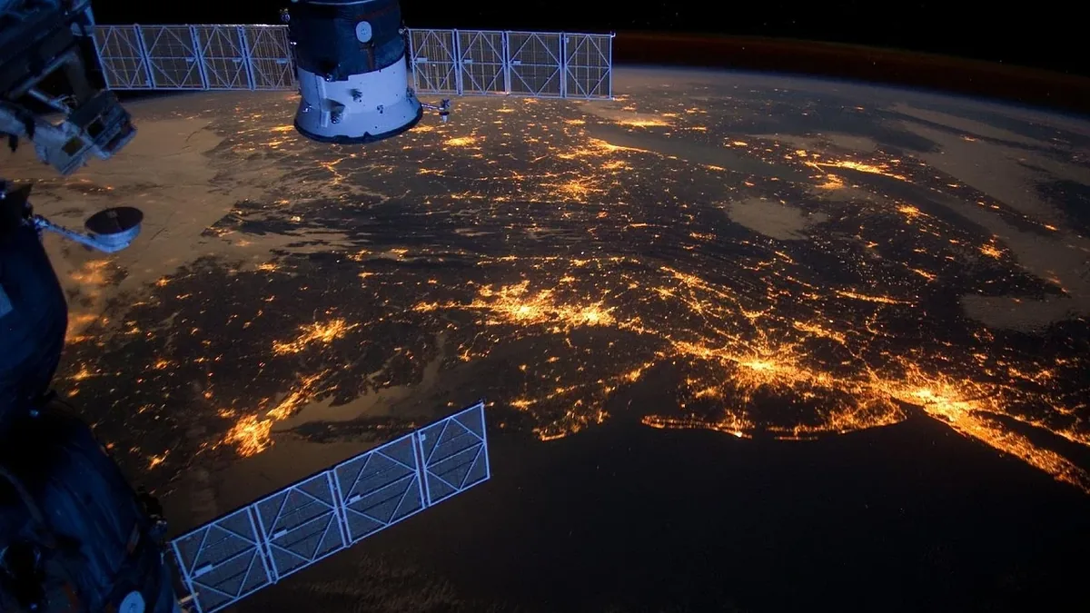 The Earth's surface from space, with a satellite and solar panels visible.