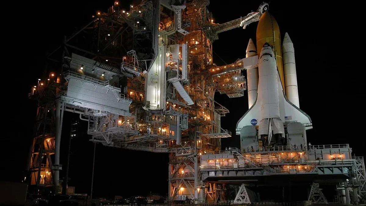 The Space Shuttle Discovery on the launch pad at Kennedy Space Center, with the shuttle's white and orange body, the external fuel tank, and