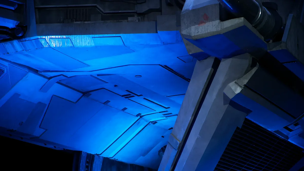 A close-up view of the front end of a large, futuristic-looking vehicle, possibly a spaceship or a futuristic car, with a blue light illuminating the interior and a dark background.