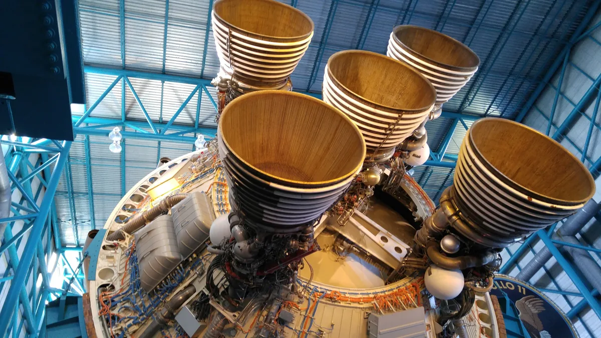 The top of a rocket engine with four large cylindrical nozzles, likely part of a space launch vehicle.